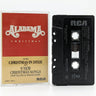 A vintage RCA cassette tape and its paper sleeve for 'Alabama Christmas' by Alabama, displayed on a white surface.