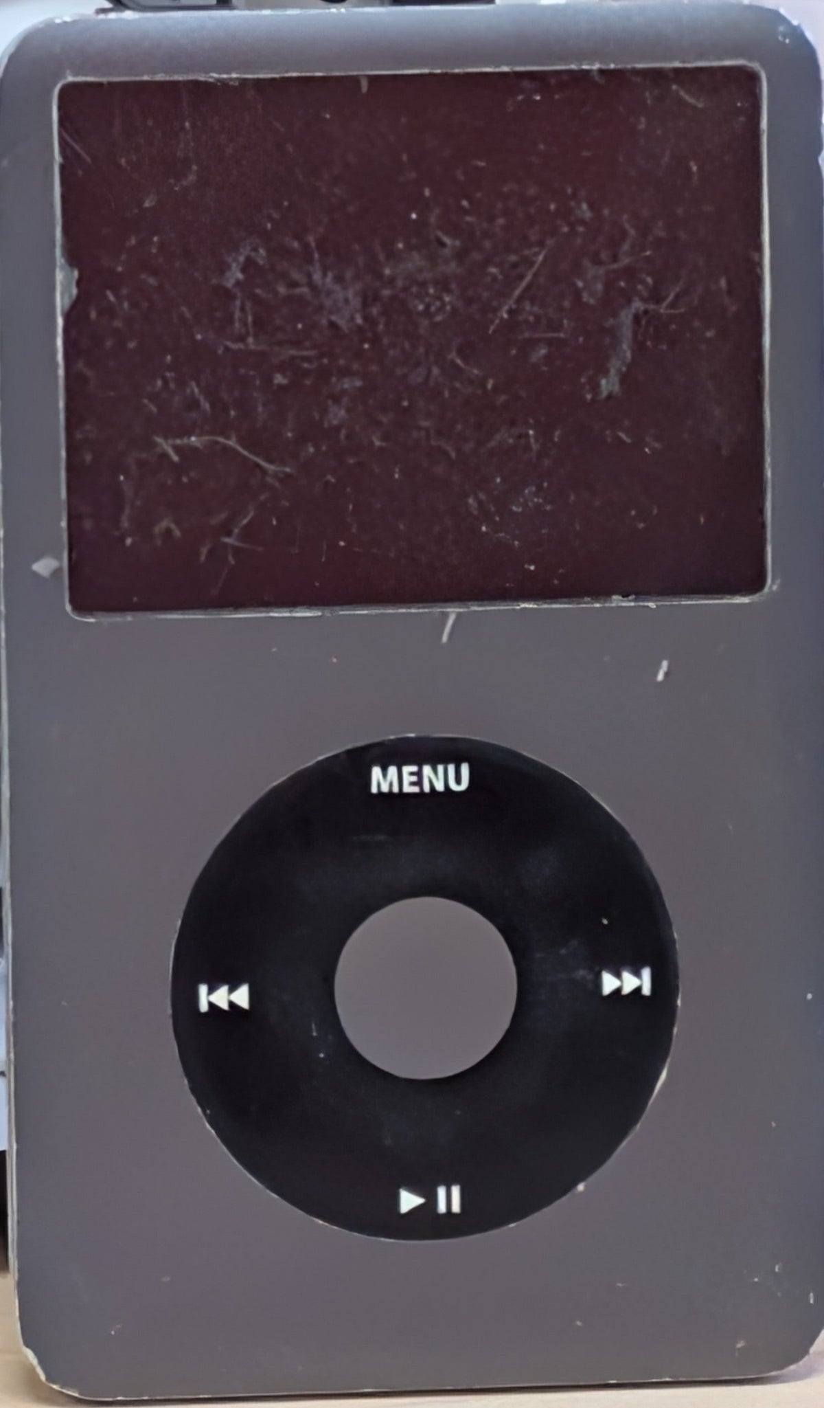 A used black Apple iPod Classic portable player with a scratched screen