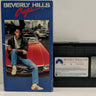 VHS tape and box cover for the movie Beverly Hills Cop, featuring an image of the main character with a red sports car in the background.