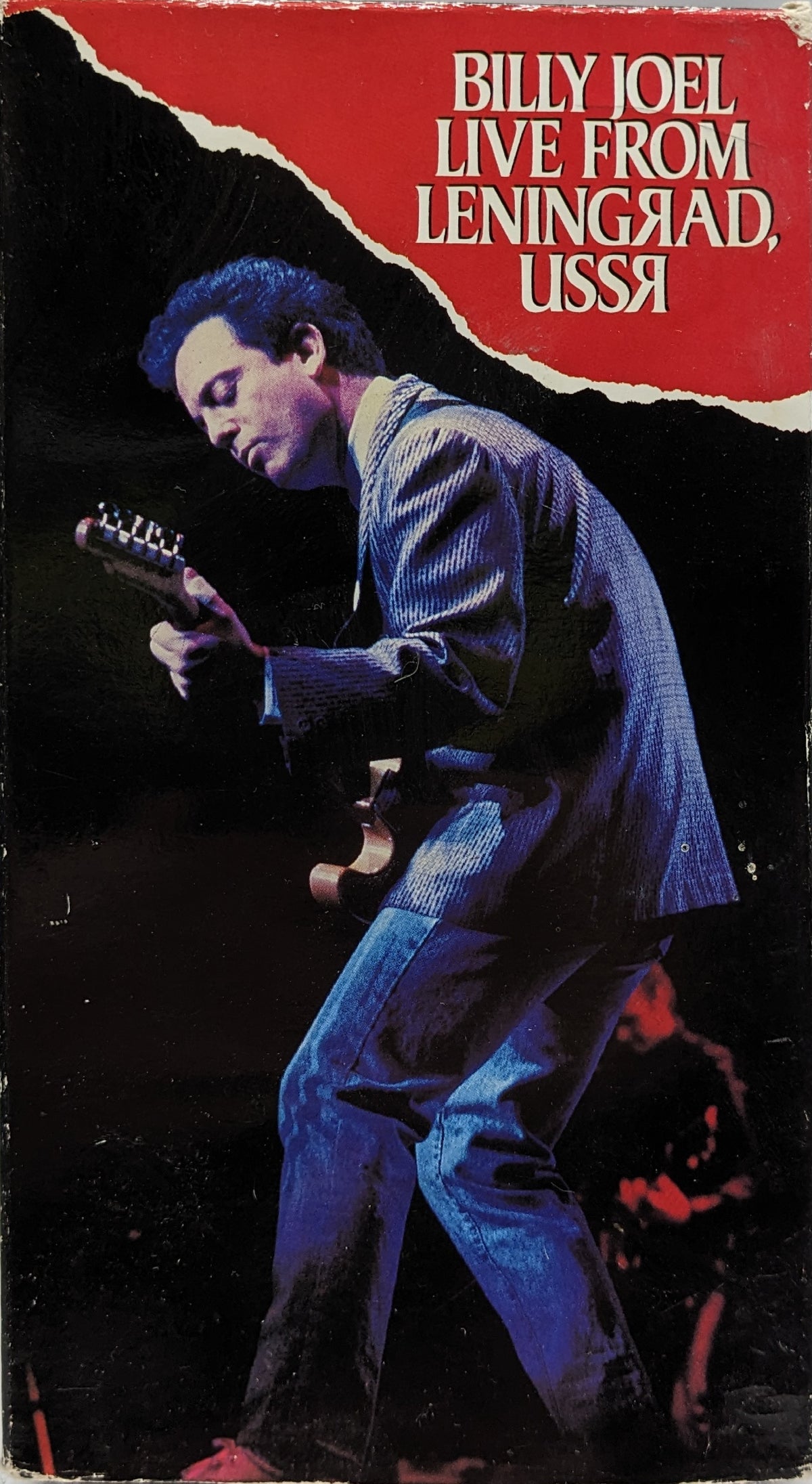 The image features the cover of the VHS titled "Billy Joel Live From Leningrad USSR." The cover depicts a black and white photo of Billy Joel in mid-performance attire, singing and playing a guitar.