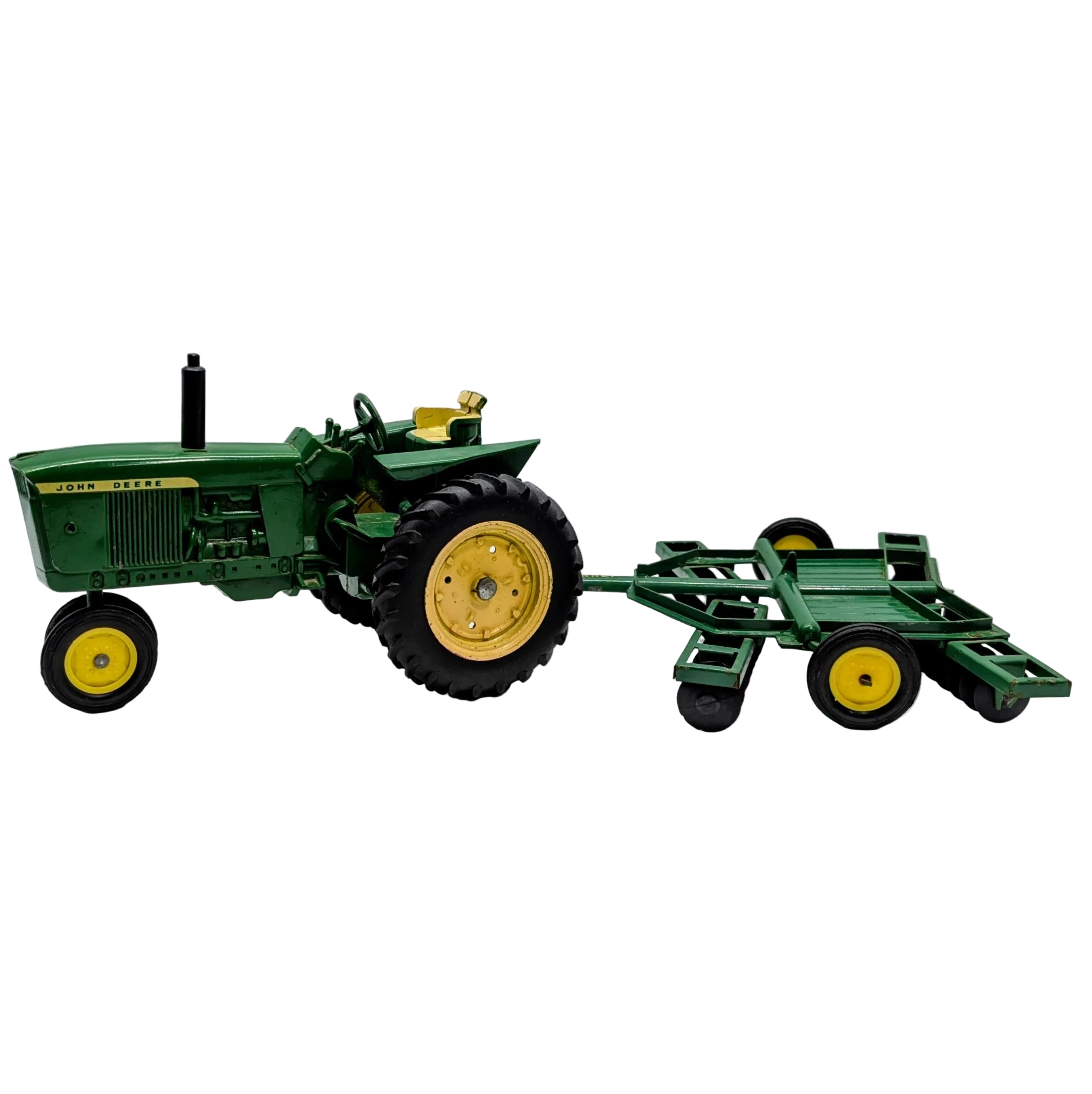 Model green tractor with a plow on a white background