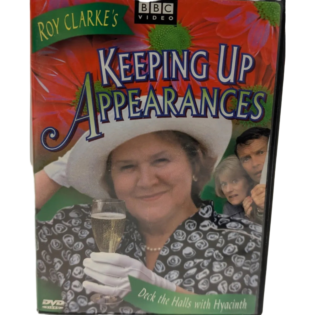 DVD cover for 'Roy Clarke's Keeping Up Appearances' on BBC Video, featuring a smiling woman in a large white hat and patterned blouse holding a glass, with colorful floral background graphics and title text.