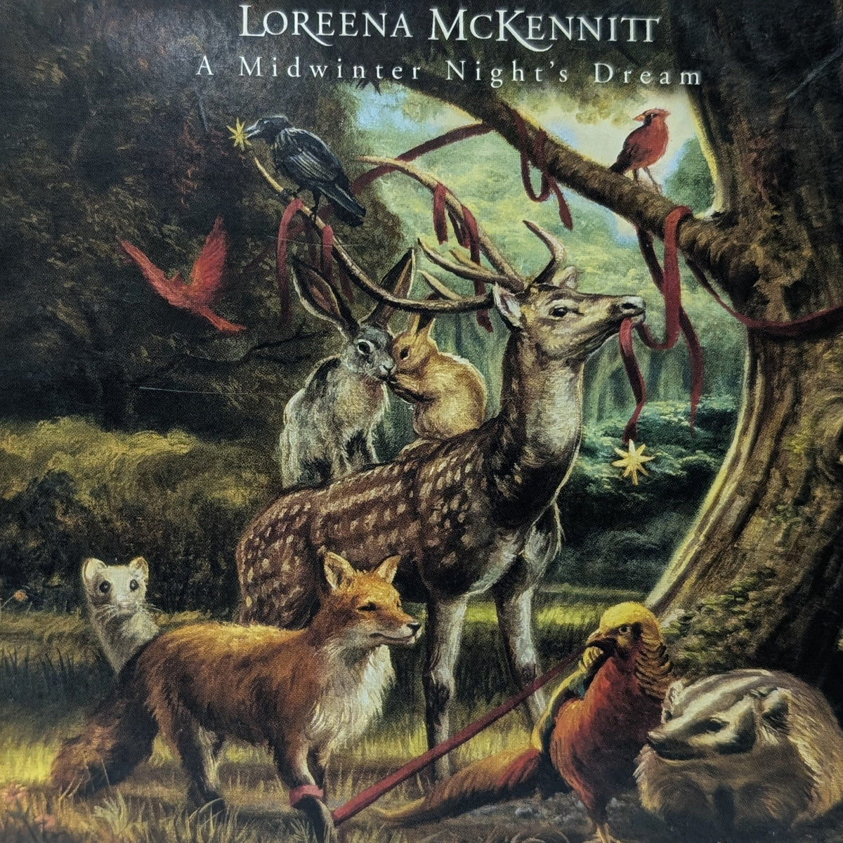 Album cover for 'A Midwinter Night's Dream' by Loreena McKennitt, featuring a detailed woodland illustration with a deer, fox, bird, owl, and other animals under a tree.