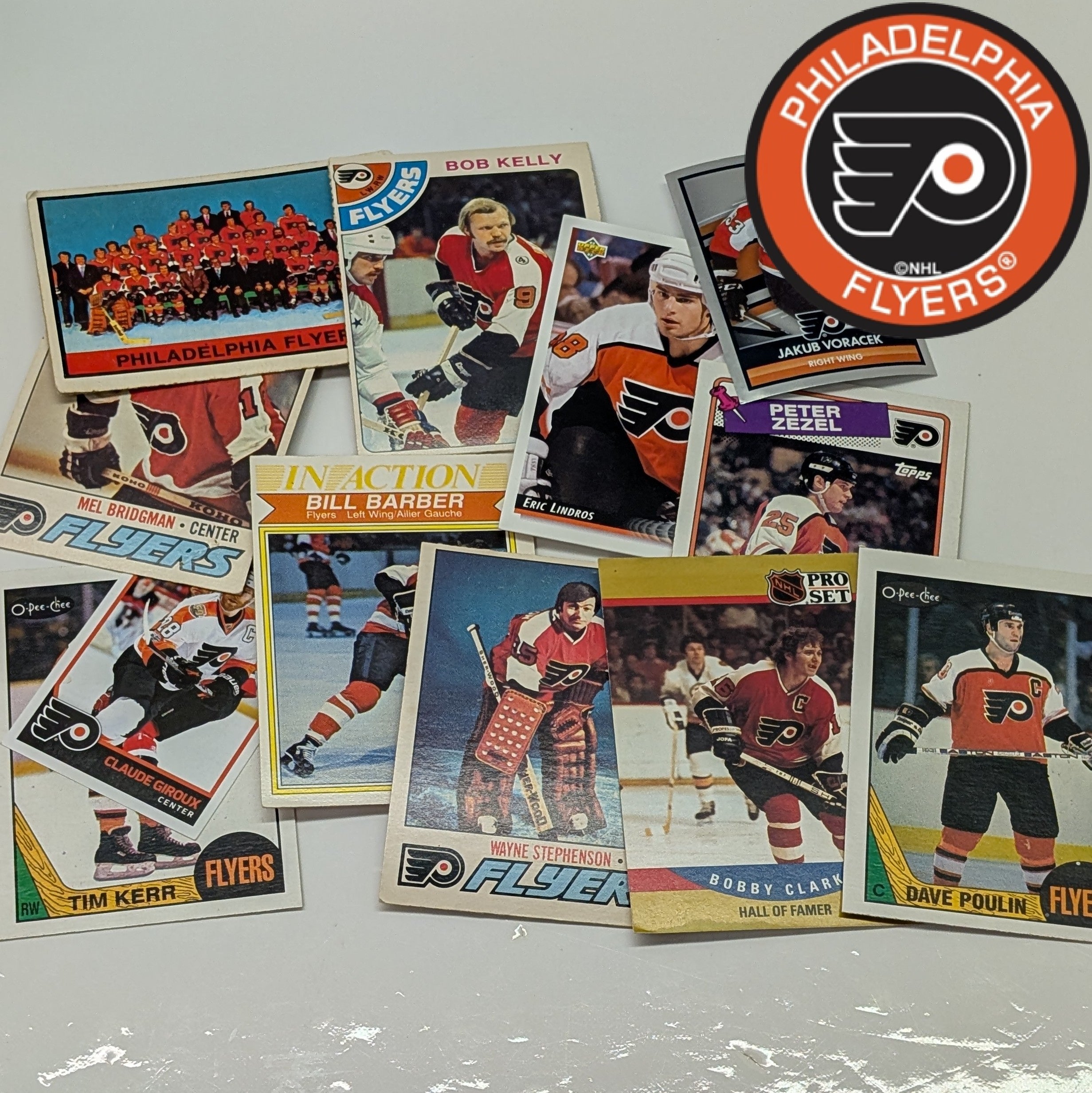Collection of Philadelphia Flyers hockey trading cards on a white surface with the Flyers logo.