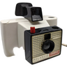 A Polaroid Swinger Model 20 Instant Camera with a black front, silver body, and white back. The camera features a meniscus lens, a red aperture control thumb wheel, and a flash-bulb socket.