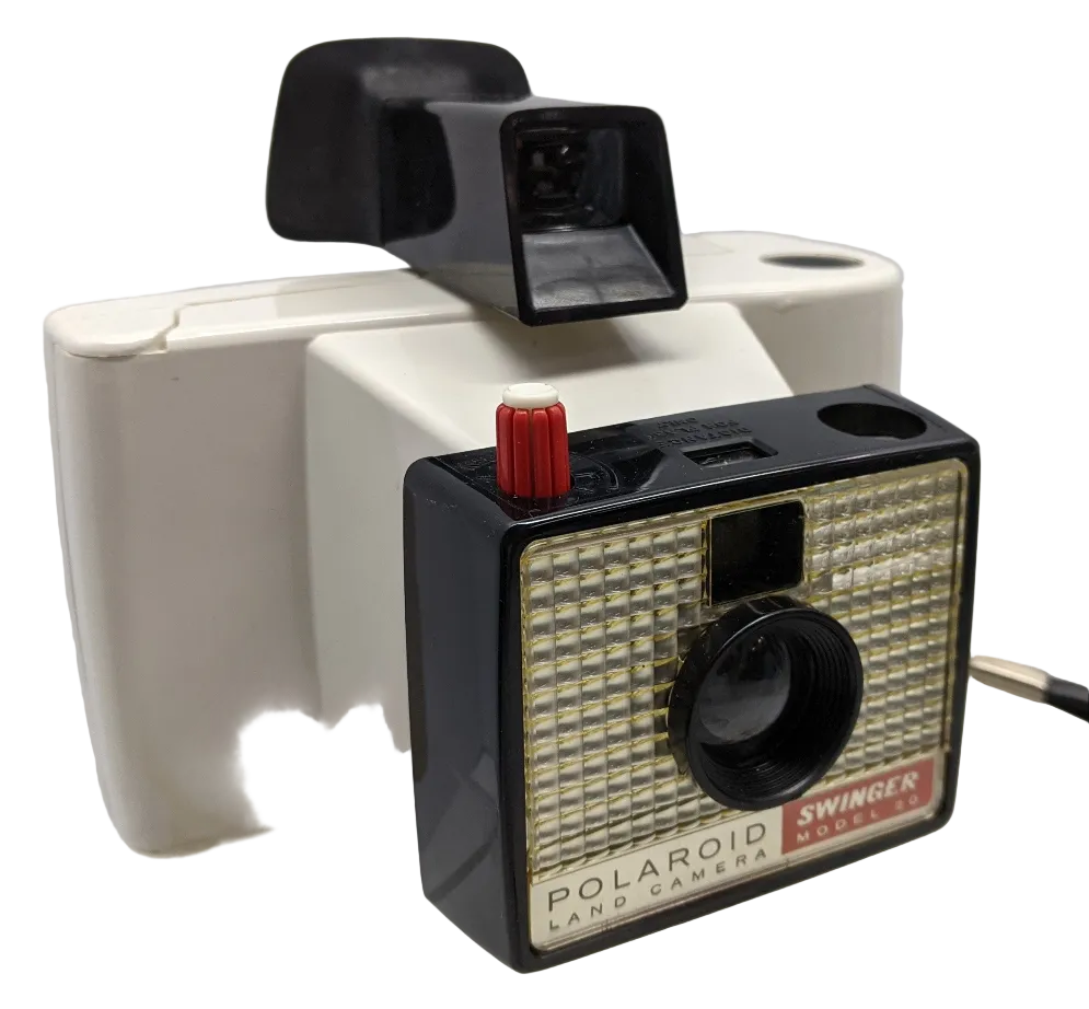A Polaroid Swinger Model 20 Instant Camera with a black front, silver body, and white back. The camera features a meniscus lens, a red aperture control thumb wheel, and a flash-bulb socket.