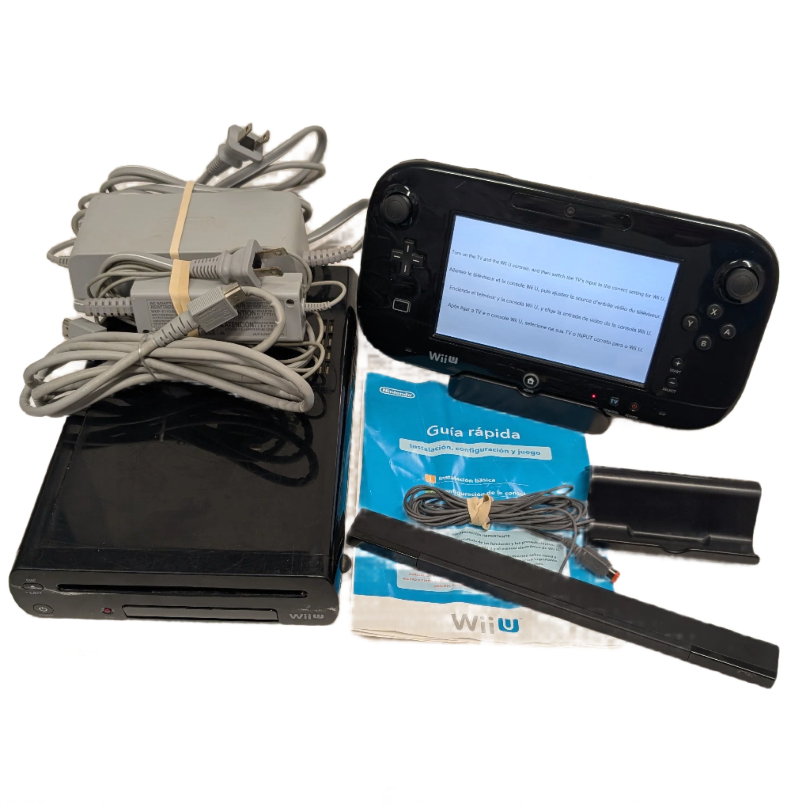 Wii U gaming console with controller, cables, and manual on a white surface