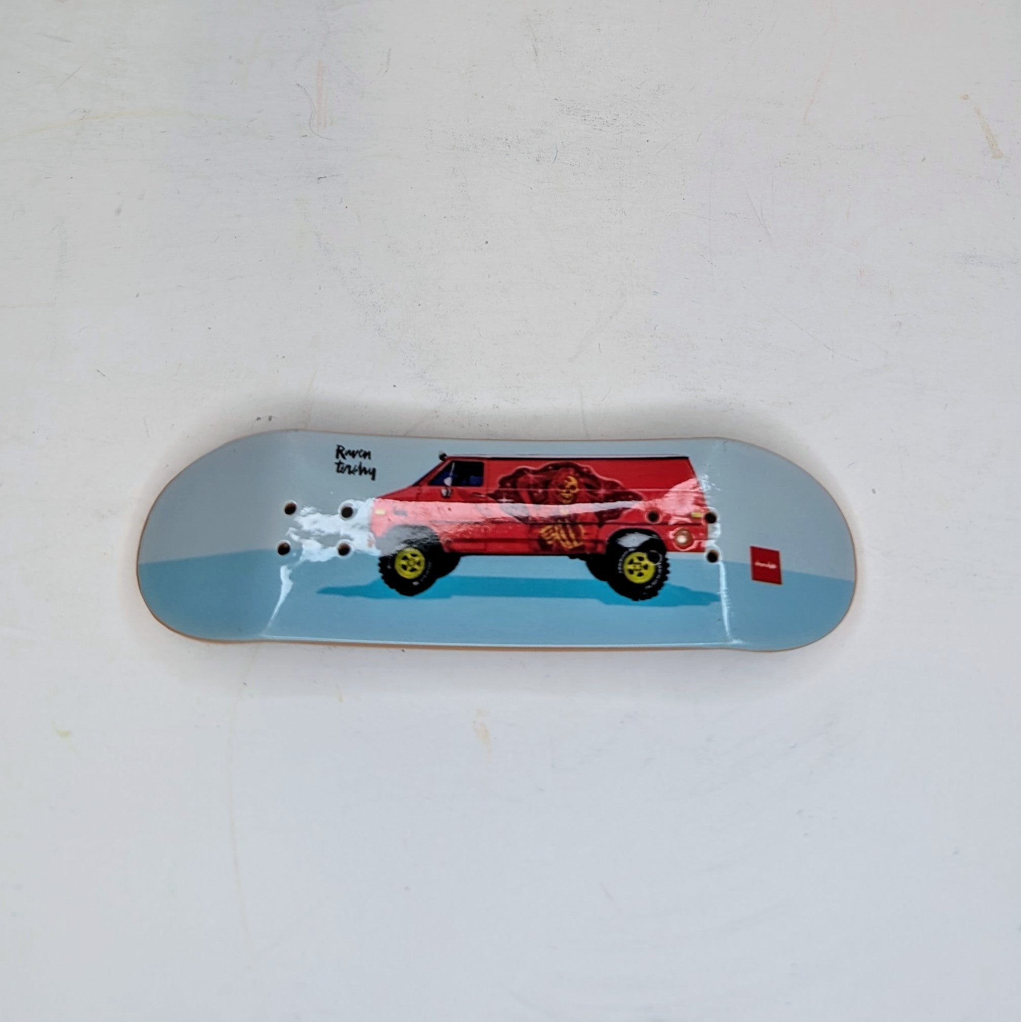 Skateboard deck with a red car design on a light blue background
